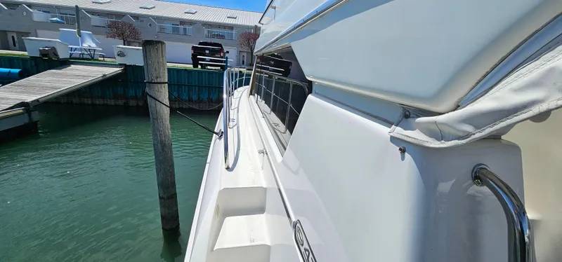 Slide: The Image of 2003 Silverton 42 Convertible yacht docked at marina, side view with clear water. - 15
