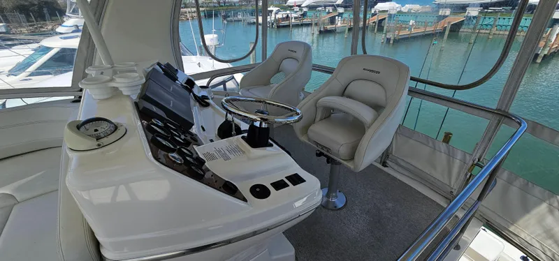Slide: The Image of 2003 Silverton 42 Convertible yacht helm with plush seating and marina view. - 20