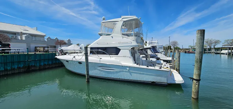 Slide: The Image of 2003 Silverton 42 Convertible yacht docked in a marina under a clear blue sky. - 3