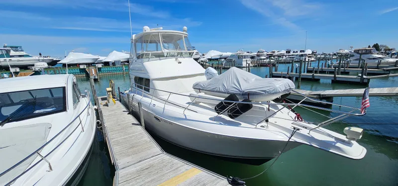 Slide: The Image of 2003 Silverton 42 Convertible yacht docked at marina under clear blue sky. - 4
