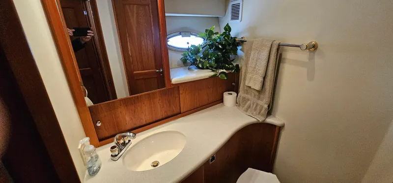 Slide: The Image of 2003 Silverton 42 Convertible yacht bathroom with sink, mirror, towel, and porthole window. - 44