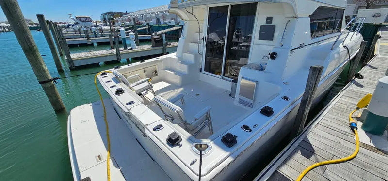 Slide: The Image of 2003 Silverton 42 Convertible yacht docked at marina, featuring spacious deck and modern design. - 5