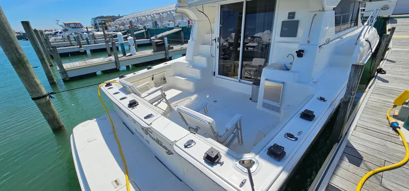 Slide: The Image of 2003 Silverton 42 Convertible yacht docked at marina, featuring spacious deck and seating area. - 7
