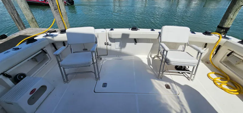 Slide: The Image of 2003 Silverton 42 Convertible boat deck with chairs, docked by the water. - 8