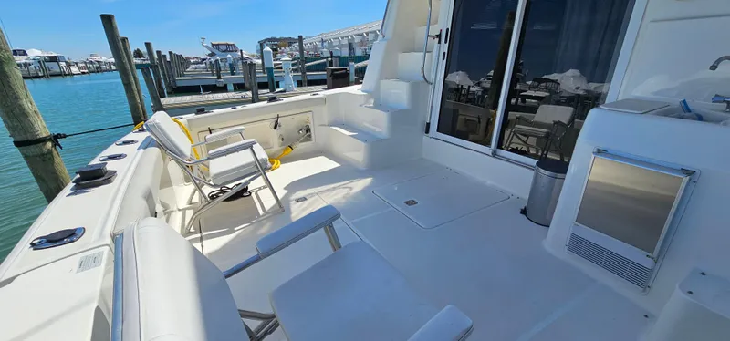 Slide: The Image of 2003 Silverton 42 Convertible yacht deck with seating, steps, and marina view. - 9