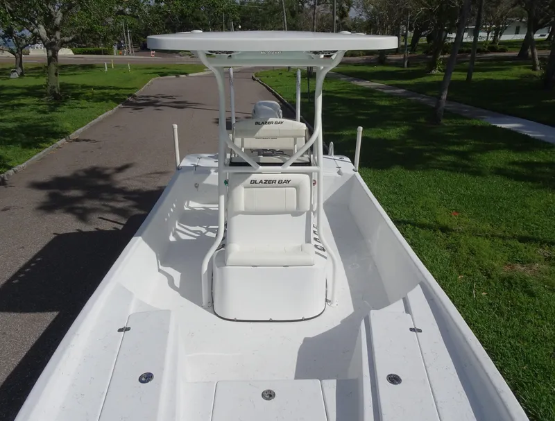 Slide: The Image of 2019 Blazer Bay 2400 boat with T-top, parked on a paved path. - 10