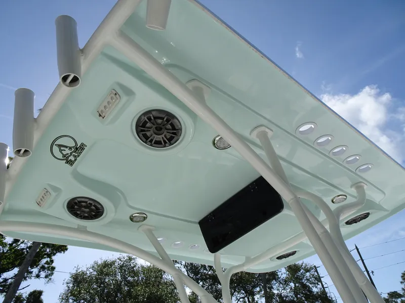 Slide: The Image of 2019 Blazer Bay 2400 boat T-top with speakers and rod holders under a clear sky. - 22