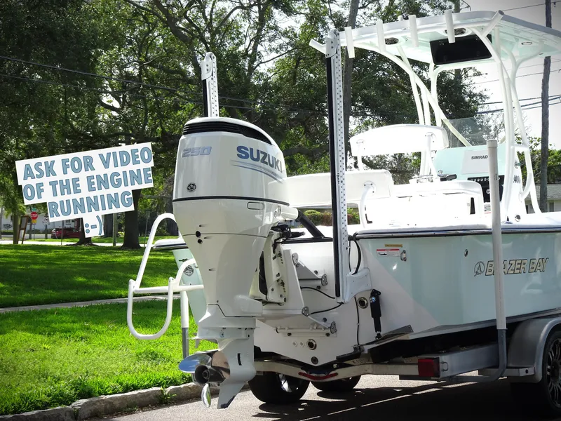 Slide: The Image of 2019 Blazer Bay 2400 boat with Suzuki engine, parked outdoors, sign reads "Ask for video of the engine running." - 3