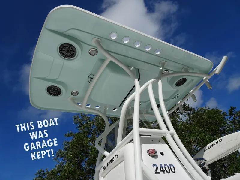 Slide: The Image of 2019 Blazer Bay 2400 boat with T-top, garage kept, under blue sky. - 8