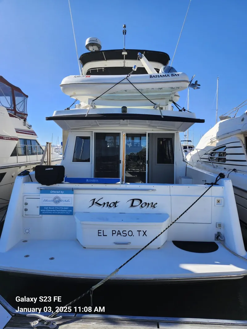 Slide: The Image of 1999 Navigator 4800 CLASSIC yacht docked at marina, featuring sleek white design and upper deck. - 3