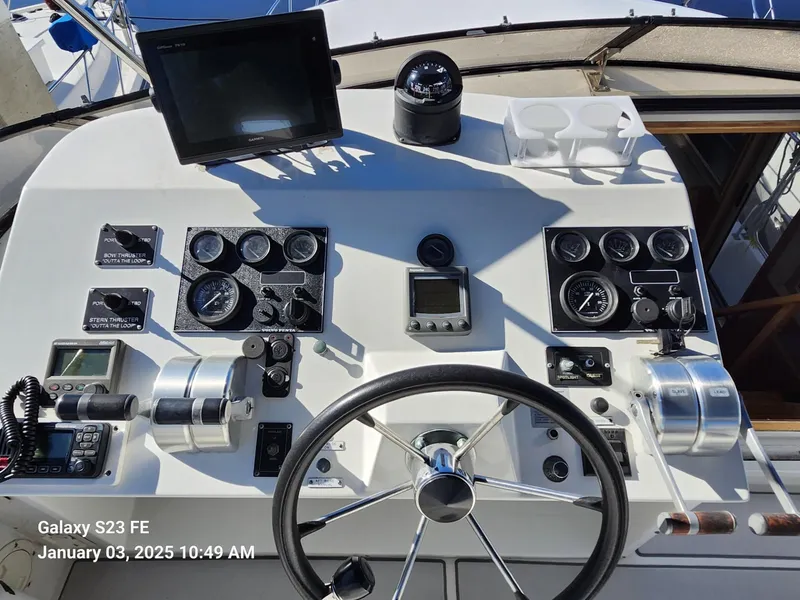 Slide: The Image of 1999 Navigator 4800 CLASSIC yacht helm with marina view, featuring white seating and control panel. - 34