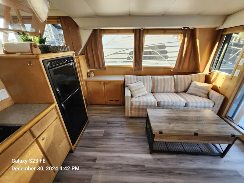 Slide: The Image of Living area of 1999 Navigator 4800 CLASSIC yacht with sofa, TV, and marina view. - 6