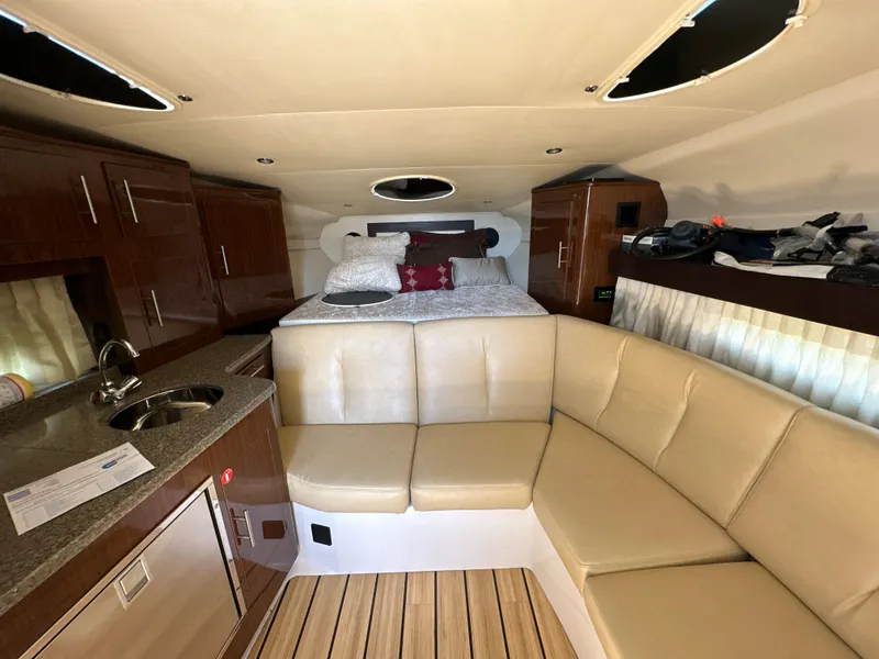 Slide: The Image of 2015 Regal 32 Express cabin interior with beige seating, kitchenette, and bed. - 15