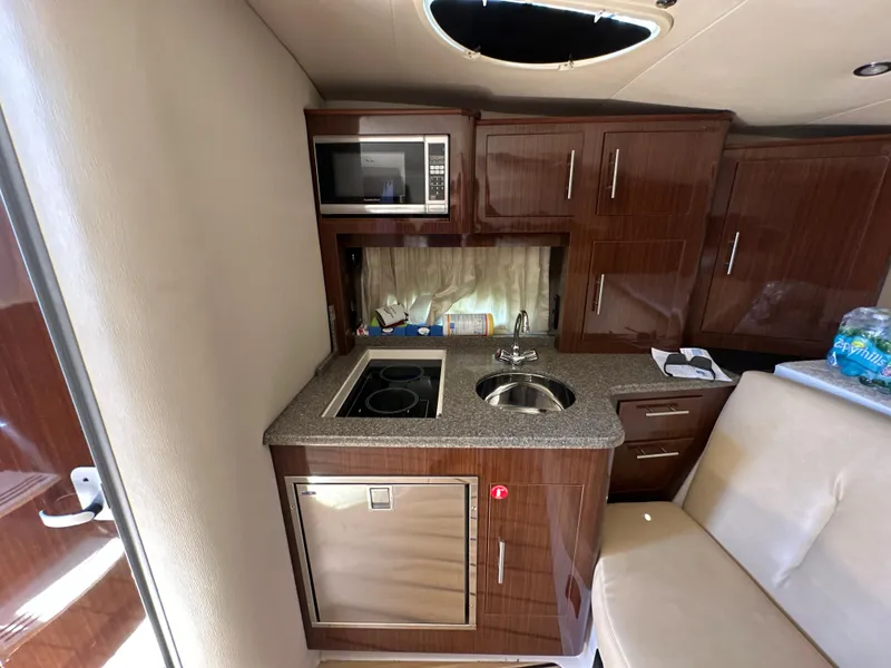 Slide: The Image of 2015 Regal 32 Express yacht interior kitchen with microwave, sink, and cabinets. - 18