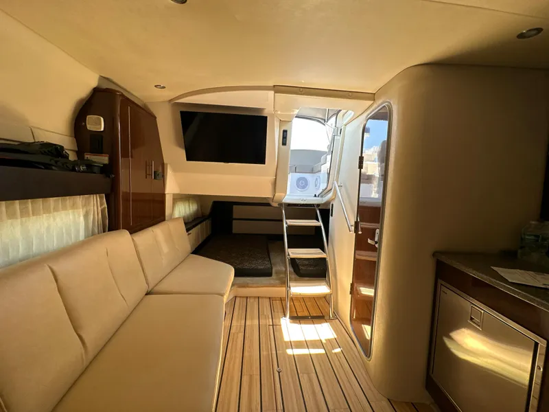 Slide: The Image of 2015 Regal 32 Express interior with beige seating, wooden flooring, and a mounted TV. - 19