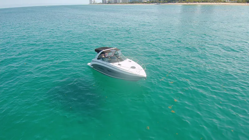 Slide: The Image of 2015 Regal 32 Express boat cruising on clear turquoise water near a distant shoreline. - 35