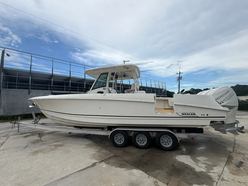 Slide: The Image of 2017 Boston Whaler 350 Outrage boat on a trailer, parked outdoors. - 1