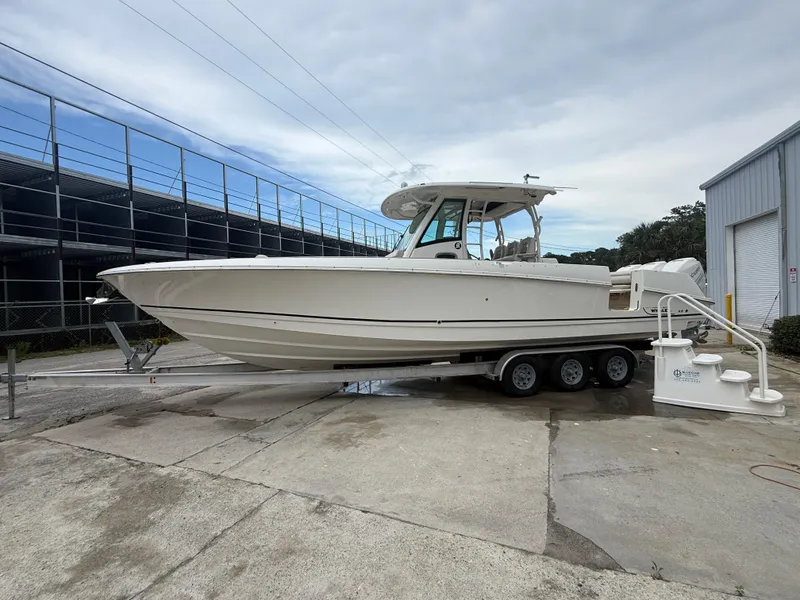 Slide: The Image of 2017 Boston Whaler 350 Outrage boat on trailer, parked outdoors. - 2