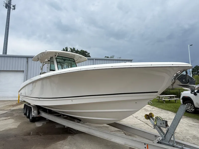Slide: The Image of 2017 Boston Whaler 350 Outrage boat on trailer, parked outdoors under cloudy sky. - 5
