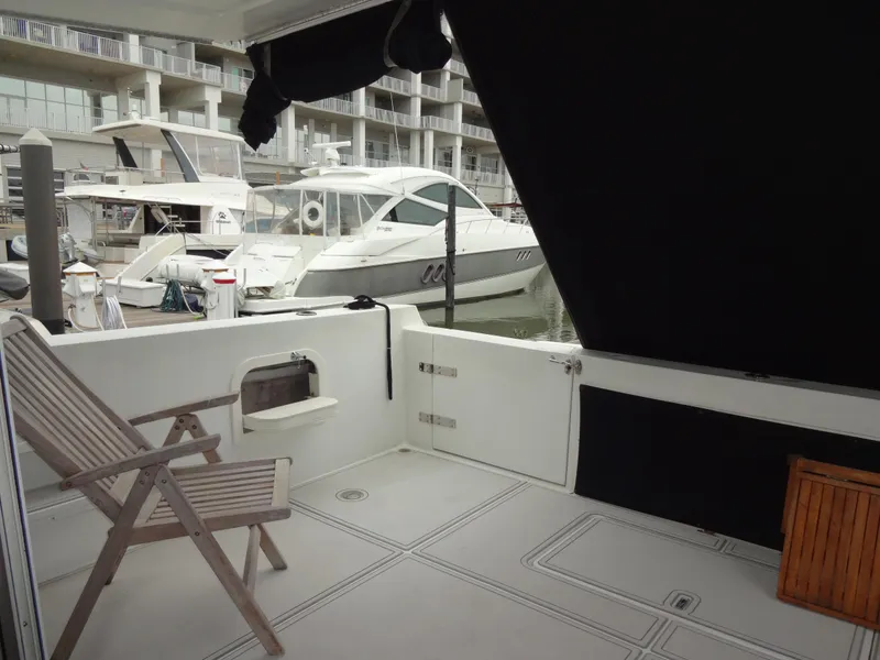Slide: The Image of Deck view of 1998 Navigator 53 Classic yacht in marina, featuring wooden chair and docked boats. - 11