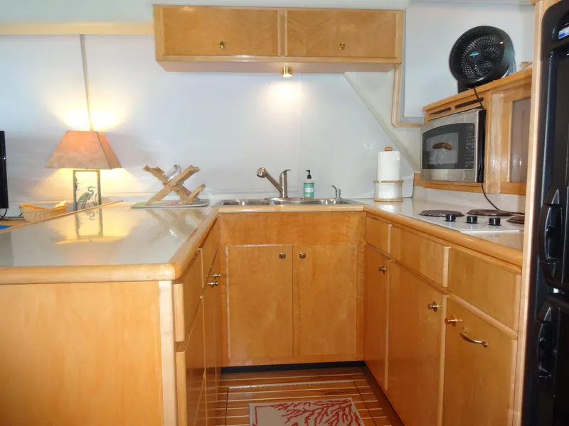 Slide: The Image of 1998 Navigator 53 Classic yacht kitchen with wooden cabinets, sink, microwave, and stovetop. - 18