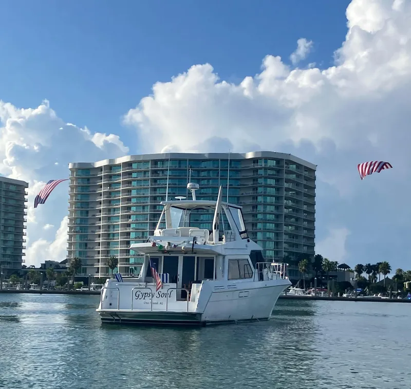 Slide: The Image of Navigator 53 Classic yacht on water with modern buildings and flags in the background. - 2