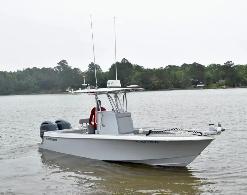 Slide: The Image of 2018 Contender 25T boat on a calm lake with forested shoreline. - 8