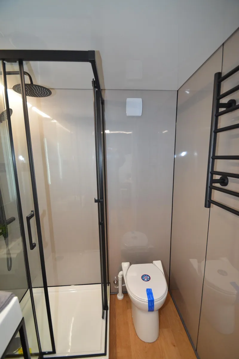 Slide: The Image of Modern bathroom with glass shower, toilet, and heated towel rack in La Mare Modern 11, 2024. - 24