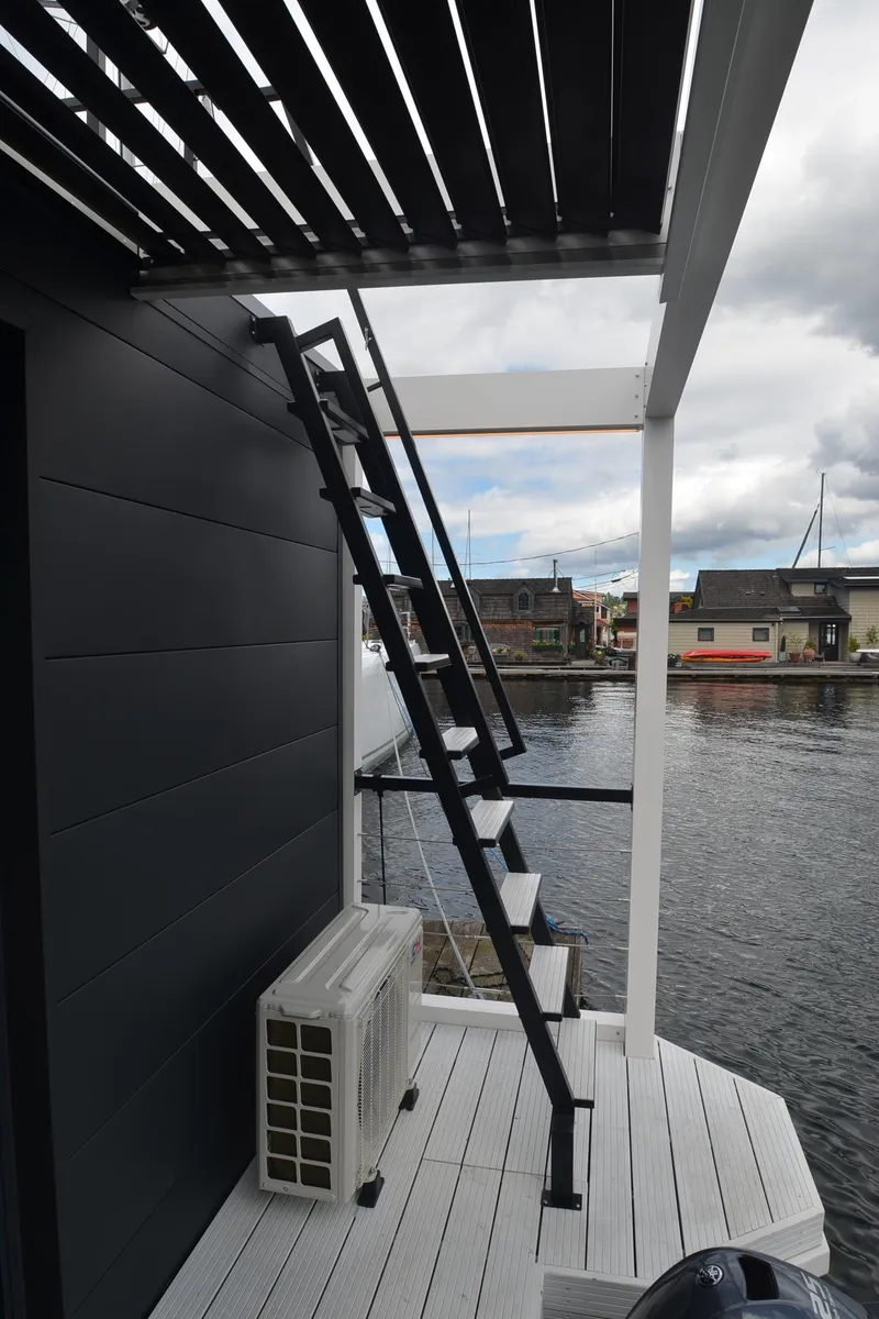 Slide: The Image of Modern houseboat with sleek black exterior, stairs, and waterfront view. La Mare Modern 11, 2024. - 32