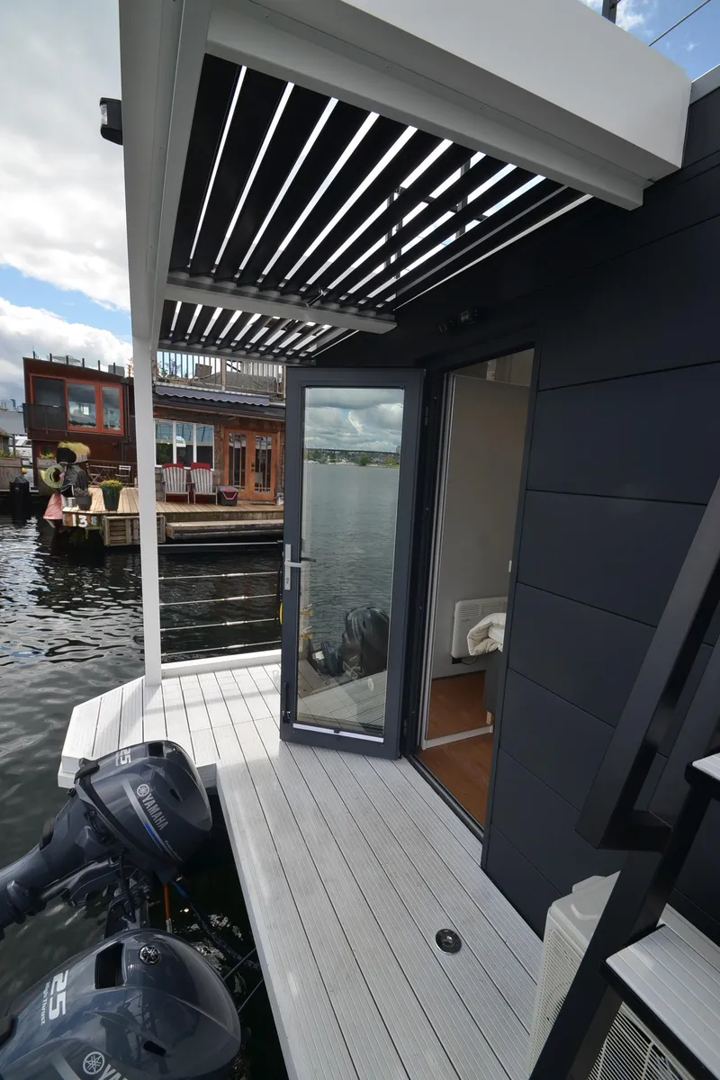Slide: The Image of La Mare Modern 11 houseboat, 2024 model, with open door and waterfront view. - 39