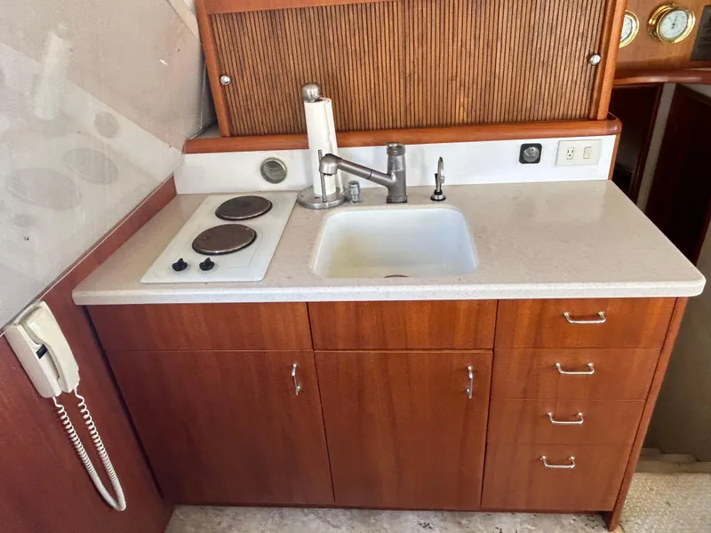 Slide: The Image of 1995 Ocean Yachts 42 Super Sport galley with sink, stove, and wooden cabinetry. - 25