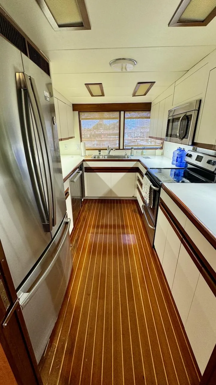 Slide: The Image of Luxurious yacht kitchen with modern appliances, wood flooring, and ample natural light. Burger 86 Raised Pilothouse. - 10