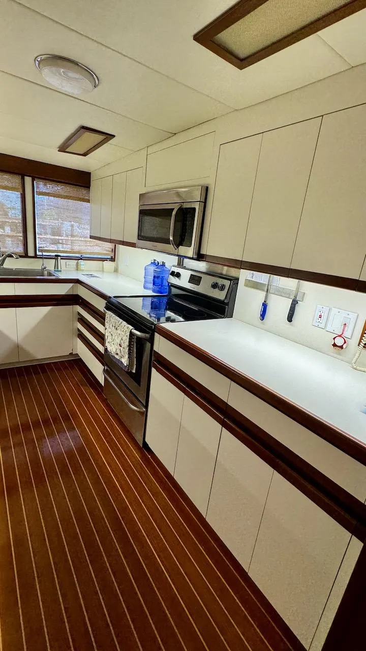 Slide: The Image of Modern kitchen interior on 1987 Burger 86 Raised Pilothouse yacht, featuring sleek cabinetry and appliances. - 12