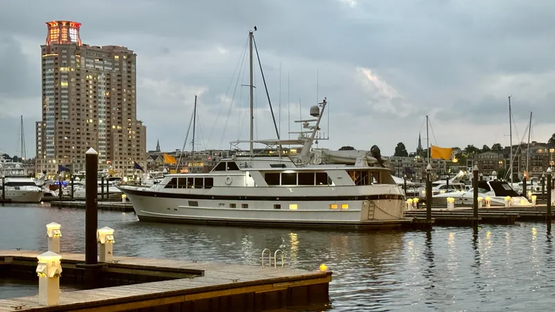 Slide: The Image of Luxury yacht "Burger 86 Raised Pilothouse" docked at marina, cityscape in background, evening setting. - 3