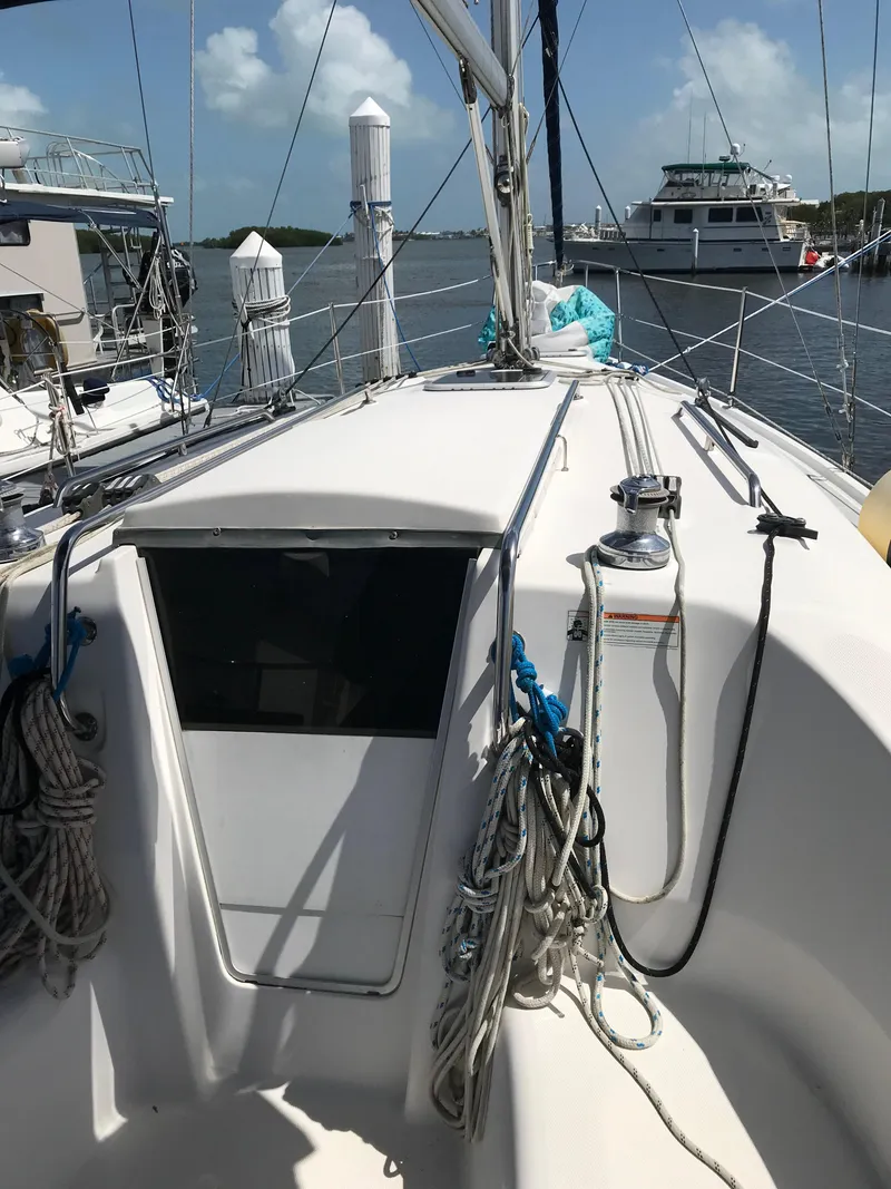 Slide: The Image of 2009 Hunter 310 sailboat deck with ropes and winch, docked in a marina. - 11