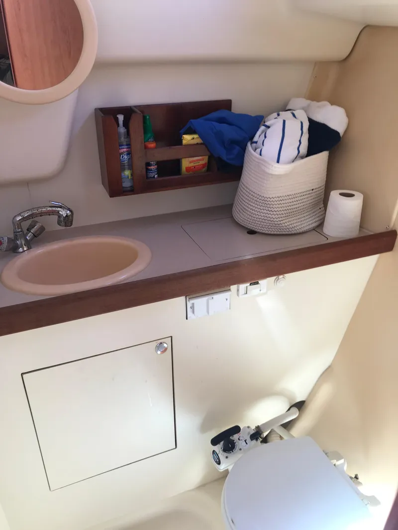 Slide: The Image of 2009 Hunter 310 boat bathroom with sink, storage shelves, and toilet. - 15