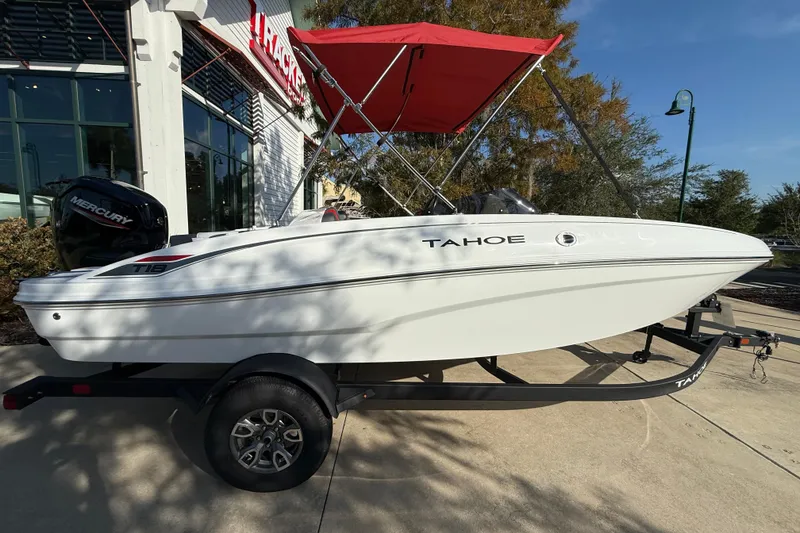 The Image of 2025 Tahoe T18 boat with red canopy on trailer, parked outside a building. - 0
