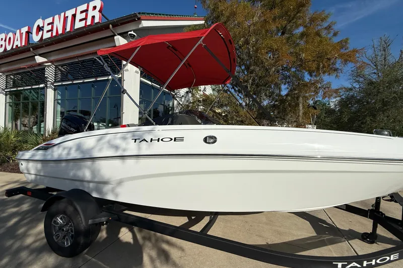 Slide: The Image of 2025 Tahoe T18 boat with red canopy at a boat center. - 1