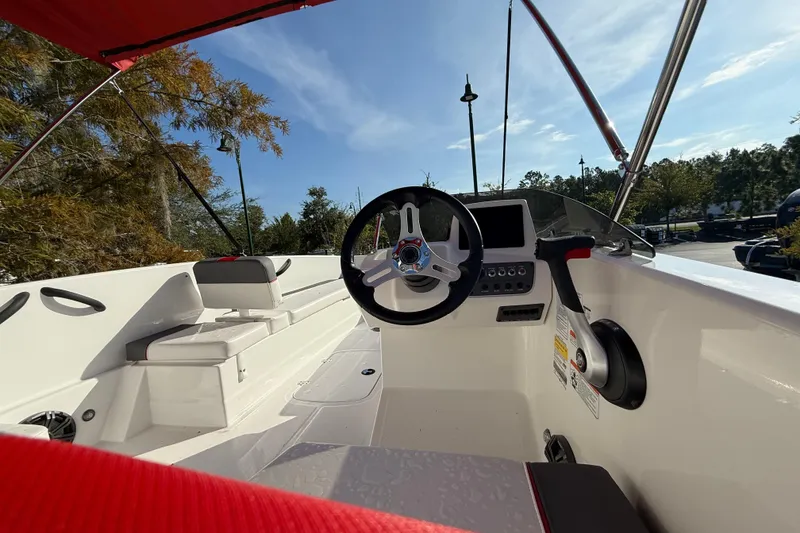 Slide: The Image of 2025 Tahoe T18 boat interior with steering wheel and seating under a red canopy. - 64