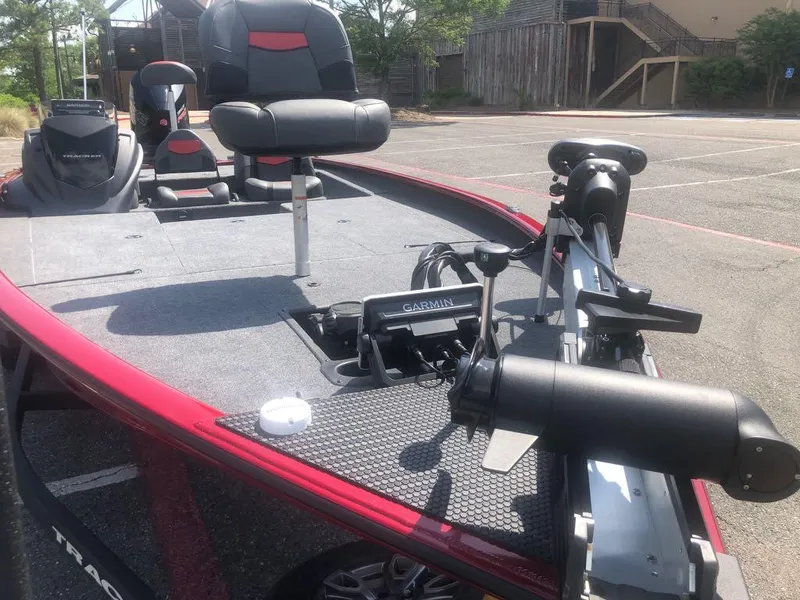 Slide: The Image of 2025 Tracker Savage 215 boat with Garmin equipment, red and black seating, parked outdoors. - 3