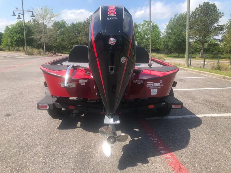 Slide: The Image of Red 2025 Tracker Savage 215 boat with powerful outboard motor in parking lot. - 9