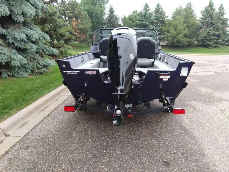 Slide: The Image of 2025 Tracker Pro Guide V-16 WT boat on trailer, parked near lush greenery. - 2