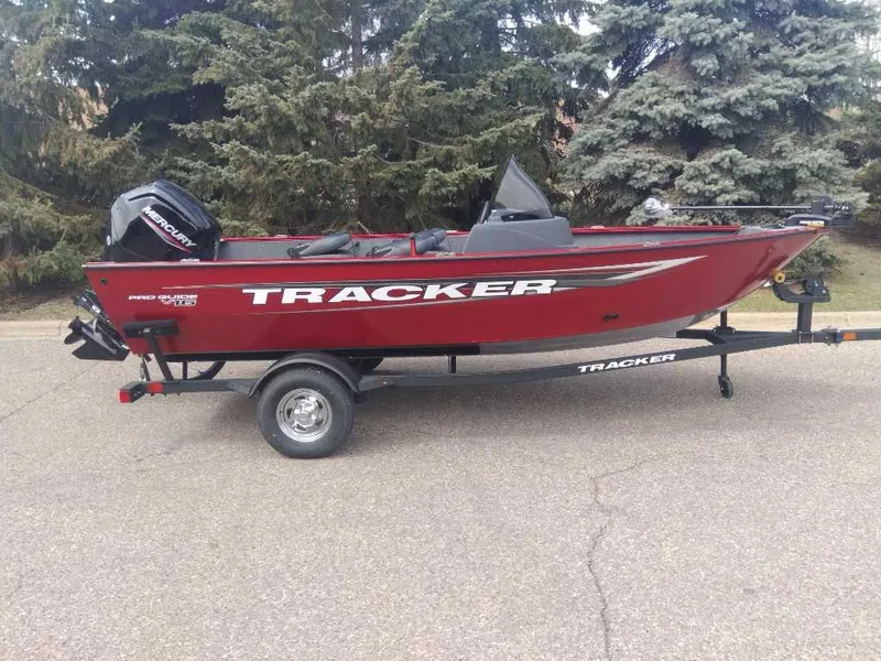 The Image of 2025 Tracker Pro Guide V-16 SC boat on trailer, red color, parked outdoors. - 0