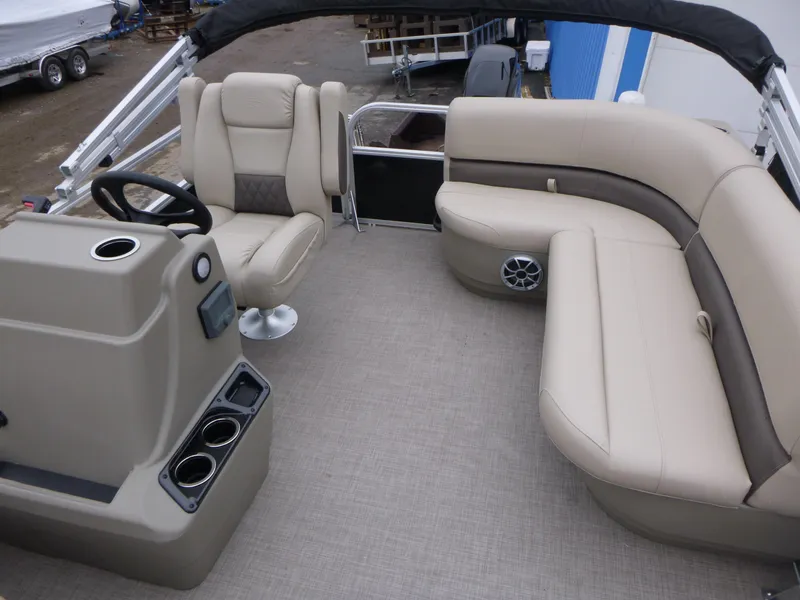 Slide: The Image of 2025 Sun Tracker Party Barge 16 DLX interior with beige seating and steering console. - 7