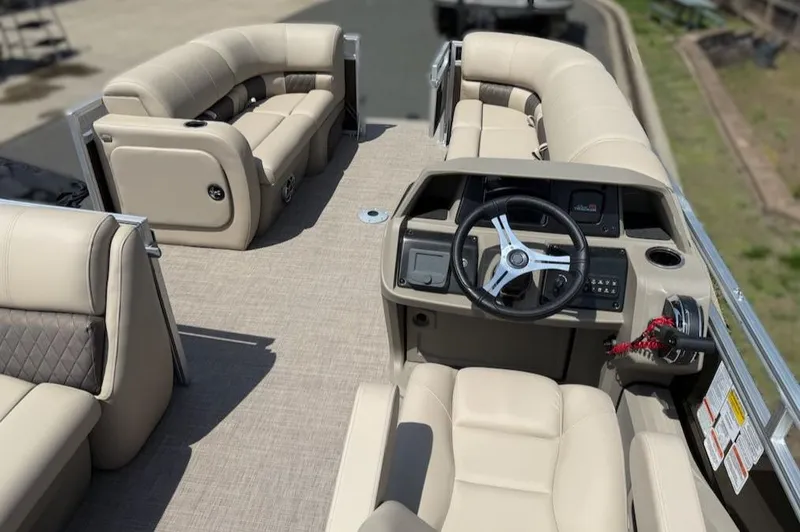 Slide: The Image of 2025 Sun Tracker SportFish 22 DLX pontoon boat interior with beige seating and steering console. - 2