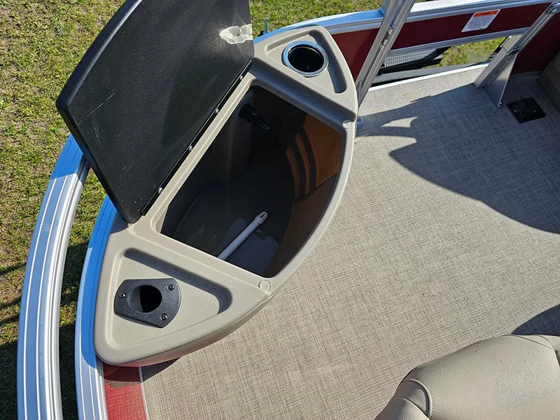 Slide: The Image of 2025 Sun Tracker Bass Buggy 18 DLX storage compartment with open lid and cup holder. - 20