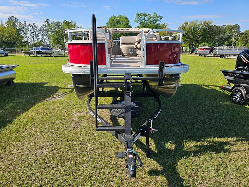 Slide: The Image of 2025 Sun Tracker Bass Buggy 18 DLX pontoon boat on trailer, parked on grass. - 4