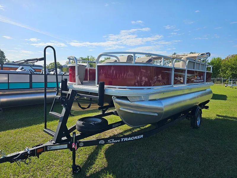 Slide: The Image of 2025 Sun Tracker Bass Buggy 18 DLX pontoon boat on trailer, parked on grass. - 5