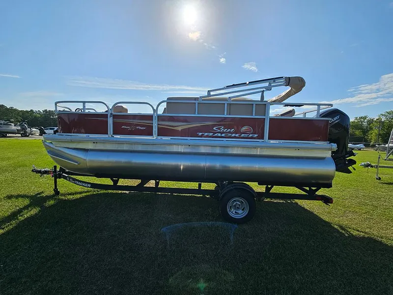 Slide: The Image of 2025 Sun Tracker Bass Buggy 18 DLX pontoon boat on grassy field under bright sun. - 6