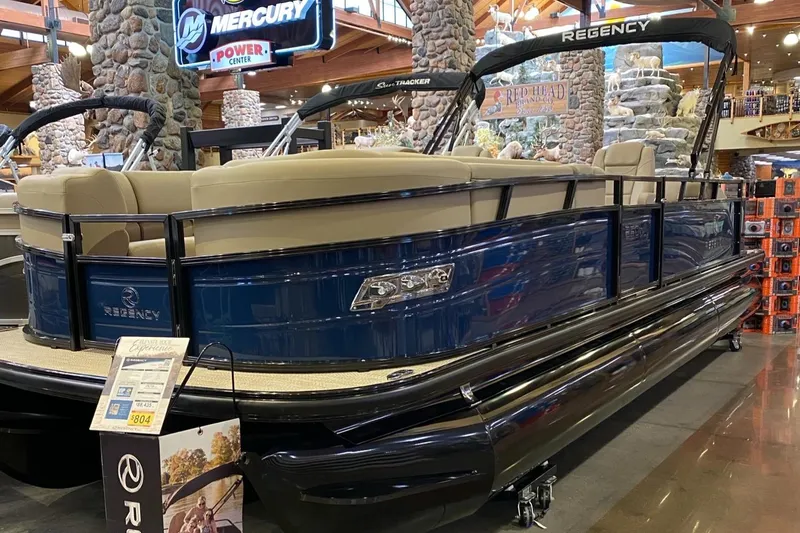 The Image of 2025 Regency 250 DL3 pontoon boat displayed indoors, featuring sleek design and comfortable seating. - 0
